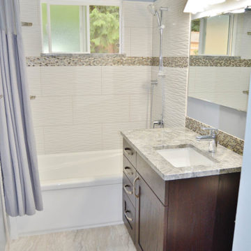 Completed bathroom with new tile floors bath tub shower tile surround and hardware and bathroom vanity with quartz countertop