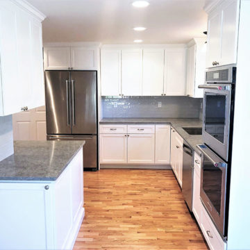 Completed kitchen remodel with an updated layout, custom cabinets, quartz counters, tile backsplash, and wood flooring