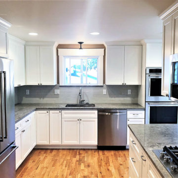 Completed kitchen remodel with an updated layout, custom cabinets, quartz countertops, tile backsplash, and wood flooring