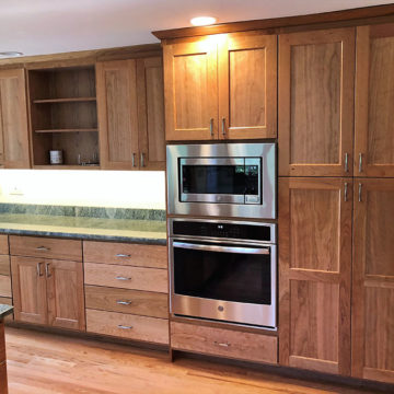 Completed kitchen with new custom built cabinets, granite counters, tile backsplash, under cabinet lighting, and refinished wood flooring