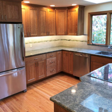 Completed kitchen with new custom built cabinets, granite countertops, tile backsplash, under cabinet lighting, and refinished wood floors