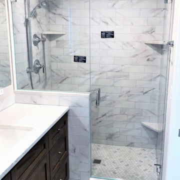 Completed new shower area with tile surround quartz corner shelve glass doors and plumbing trim